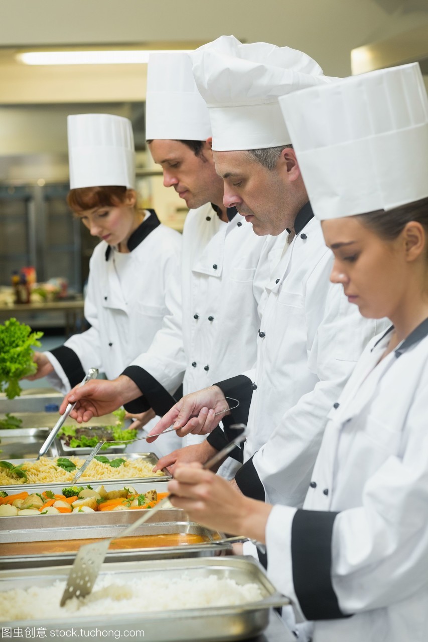 四個(gè)廚師在忙碌的廚房里服務(wù)托盤